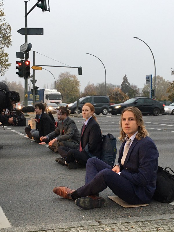 Mehrere Personen sitzen auf der Straße in Anzügen